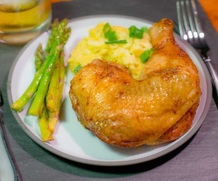 A finished smoked chicken quarter served on a plate.